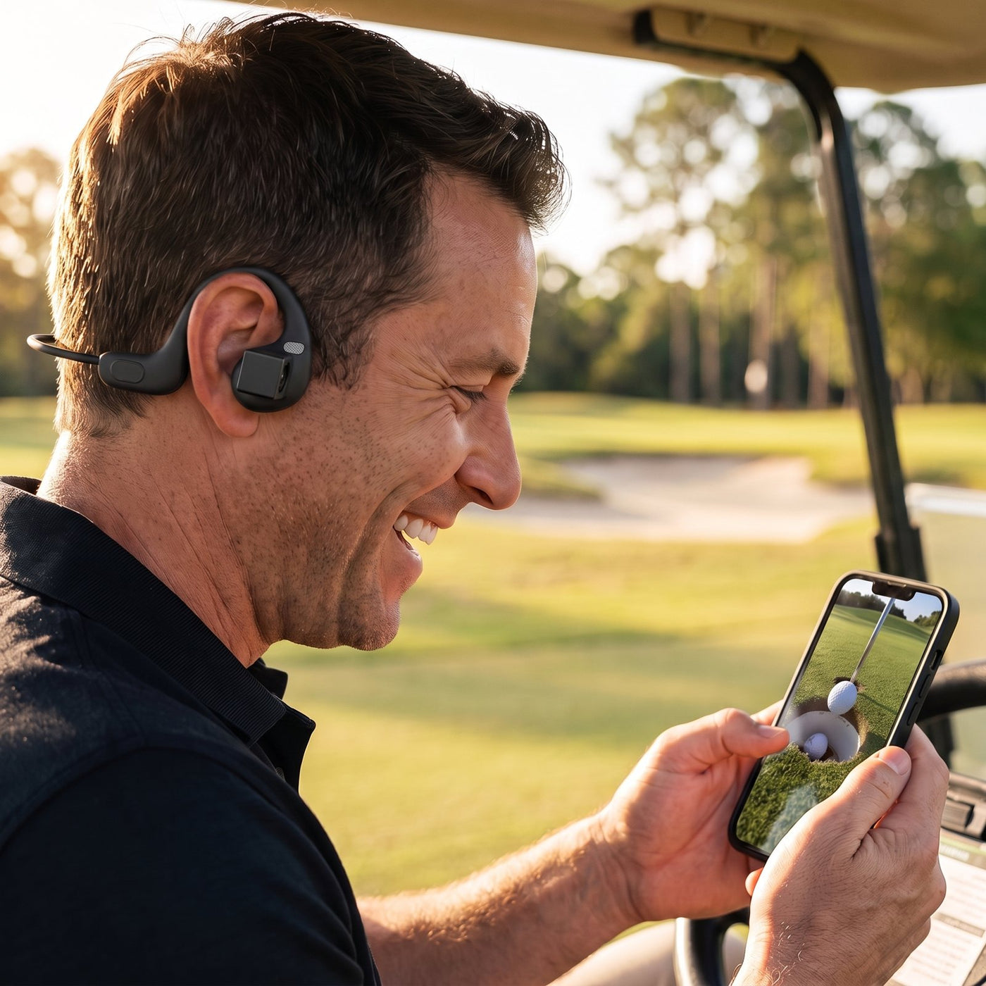 Golfer laughing at the clip on his phone in the cart